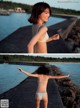 A woman in a white bikini standing on a pier by the water.