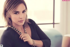 A woman in a black dress sitting on a couch.