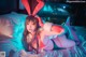 A woman in a bunny costume laying on a bed.