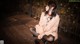 A woman sitting on a wooden deck at night.