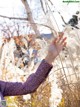 A woman in a purple dress holding a bunch of tall grass.