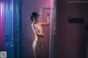 A naked woman standing in a shower with a shower head.