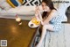 A woman sitting on the floor eating donuts and a drink.