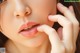 A close up of a woman's face with her hand on her chin.