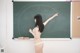 A woman in a white bikini standing in front of a blackboard.