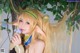 A woman with long blonde hair holding a flower in her hand.