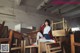 A woman sitting on top of a pile of wooden chairs.