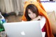 A woman in a bear costume sitting on a couch with a laptop.